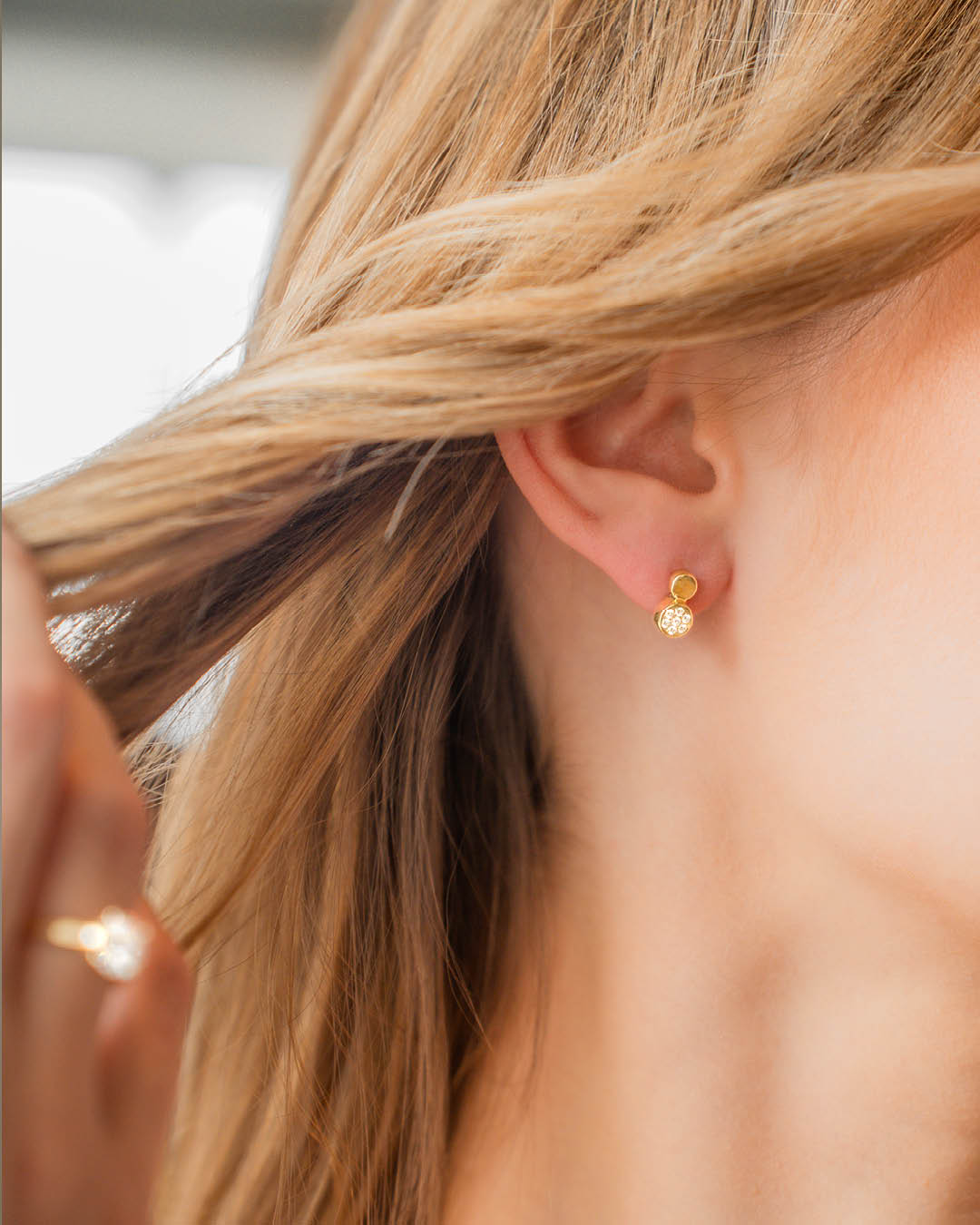 Nahaufnahme einer Frau mit blonden Haaren, die einen eleganten Doppelkreis-Ohrstecker aus 14 Karat Gelbgold mit funkelndem Diamant-Pavé trägt.